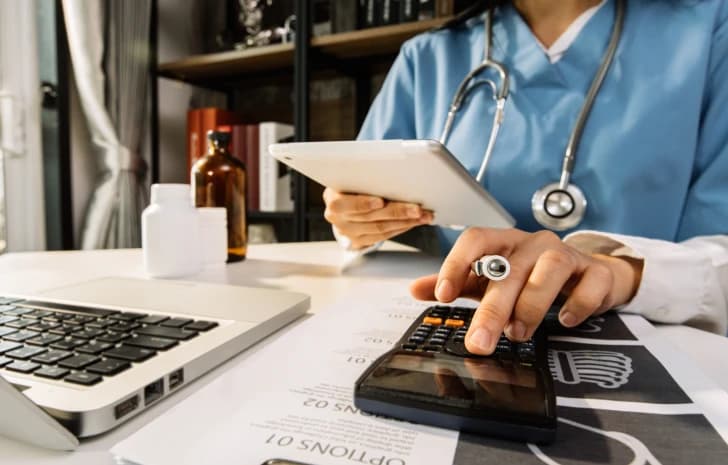 Clinician reviewing a tablet while using a calculator at a desk