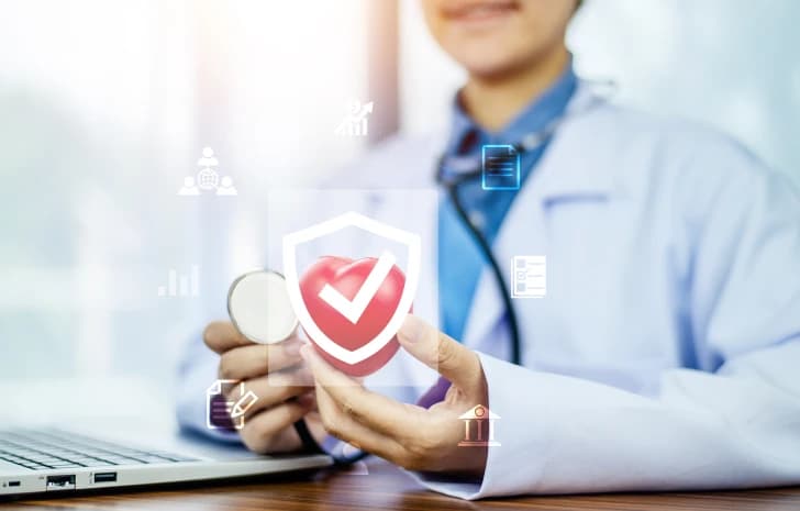 Doctor holding a shield and checkmark icon over a laptop