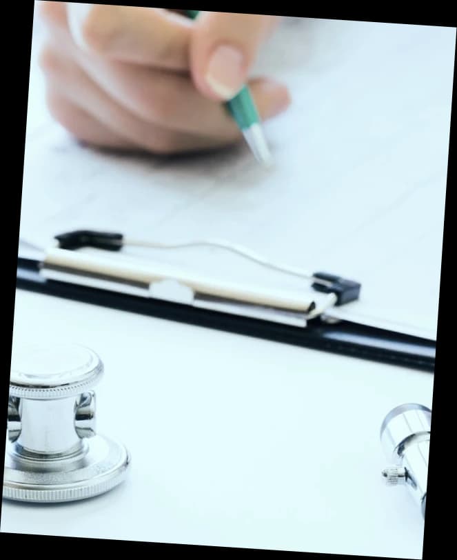 Hand writing on a clipboard next to a stethoscope