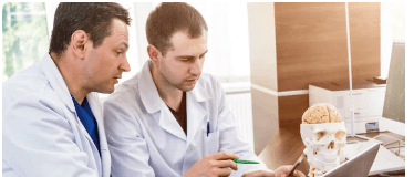 Two clinicians reviewing a claim on a laptop