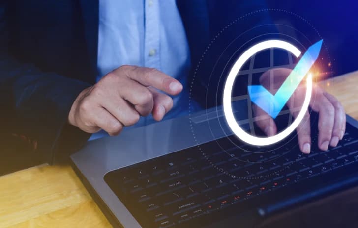 Person confirming eligibility with a checkmark icon over a laptop