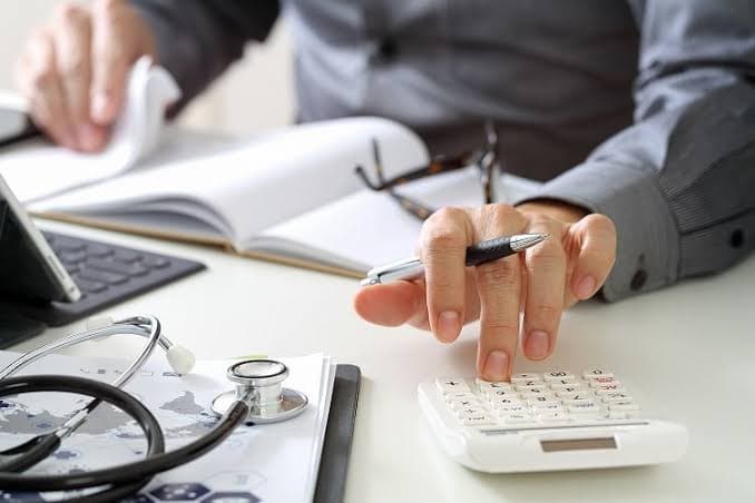 Biller using a calculator alongside patient paperwork